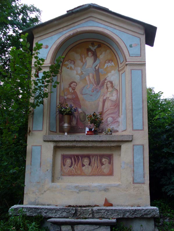 Cappelletta votiva con affresco centrale che raffigura Gesù Bambino in trionfo con la croce, in basso San Rocco a sinistra e Santa Lucia a destra, all'esterno dipinta in azzurro.