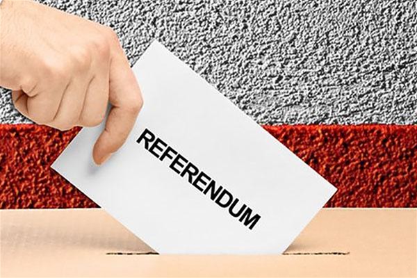 Una mano che inserisce in un'urna elettorale la scheda di votazione recante la scritta "Referendum".