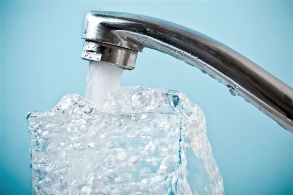 Su sfondo azzurro un rubinetto cromato da cui sgorga acqua.