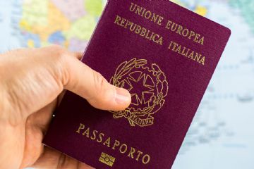 Una mano mostra un passaporto italiano.