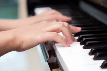 Due mani che suonano un pianoforte.