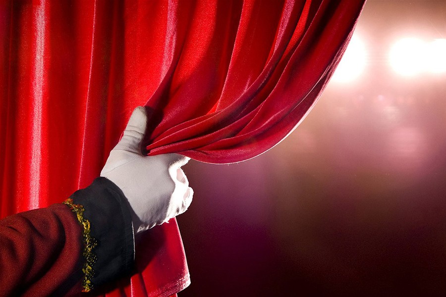 Una mano guantata scosta il sipario di un teatro.
