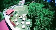 Edificio con ampio spazio esterno e campo di pallavolo su sabbia con tavoli e sedie.